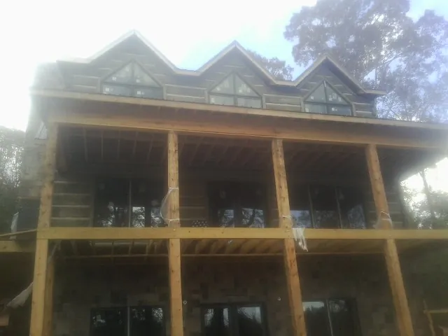 Dormers and porch framing on a large log home under construction — Roof Coating work by our crew in New Boston