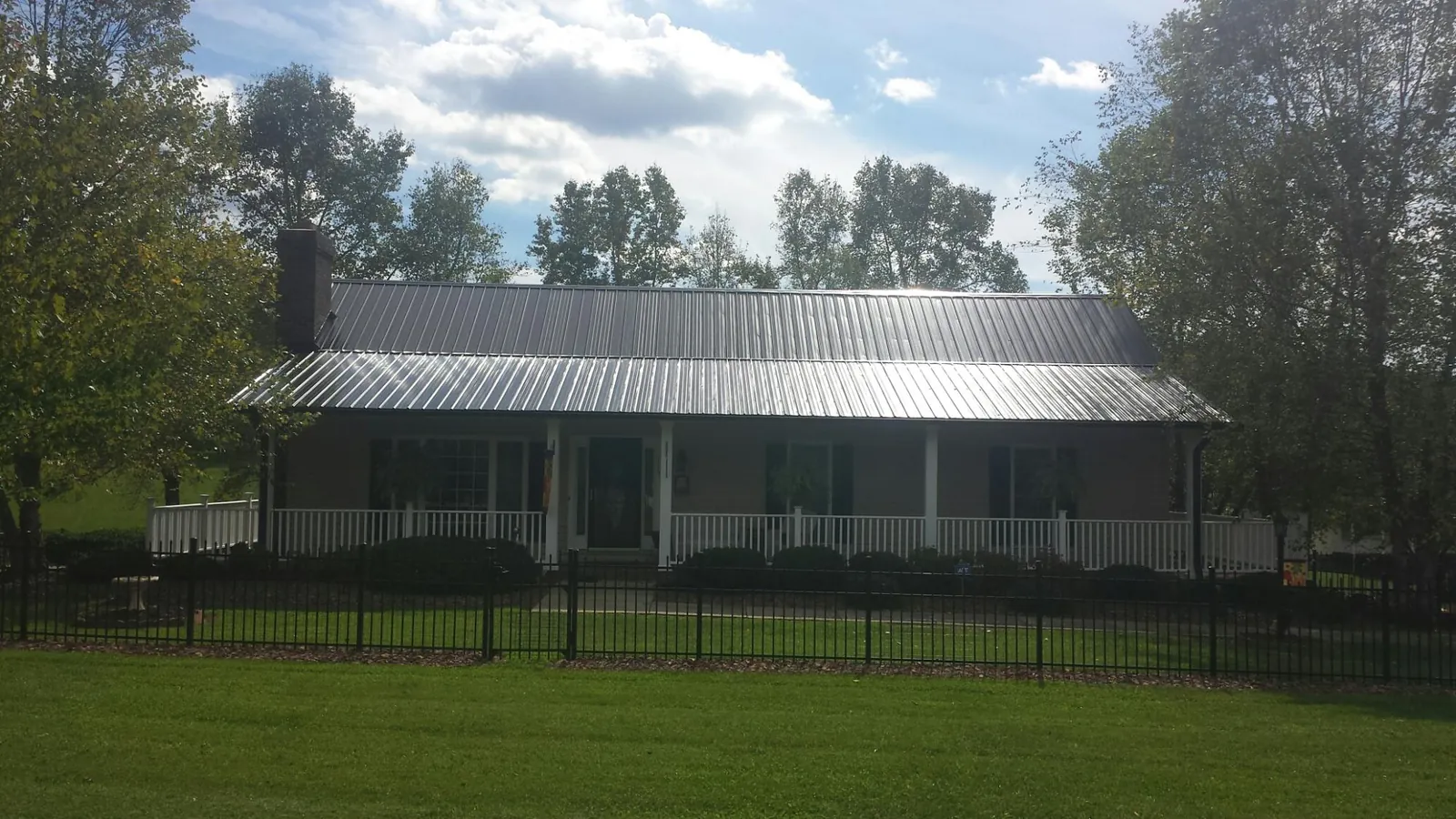 Gray metal roof on a brick ranch with a full width front porch in New Boston