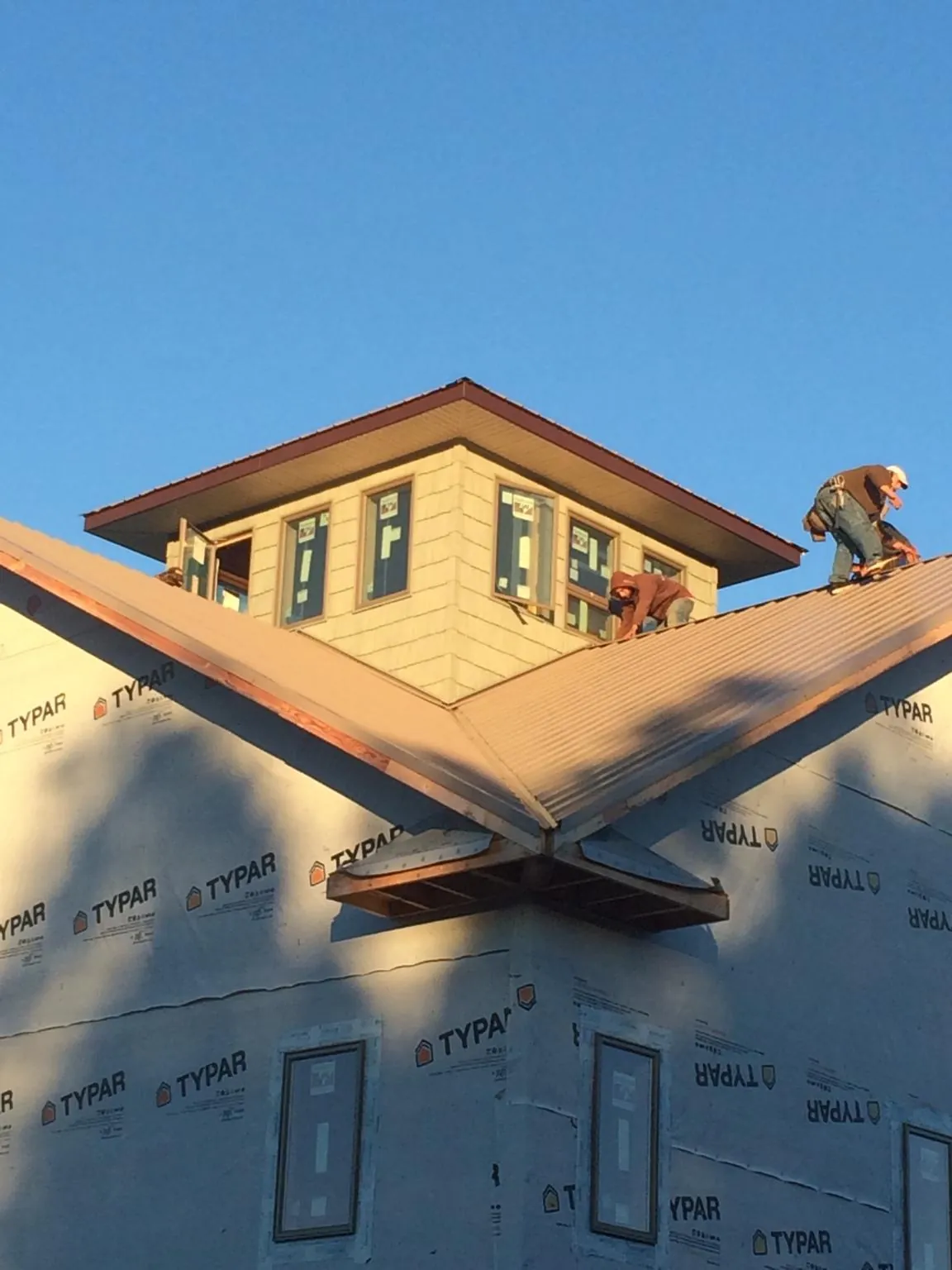 Roofers working around a rooftop cupola on a new metal roof at sunset — Roof Waterproofing in New Boston by Roofing Brothers